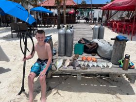 A young boy proudly displays his catch of the day, including various fish and a lobster, after a successful snorkeling adventure. Perfect for showcasing family-friendly fishing experiences.