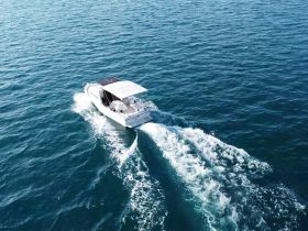 An aerial view of a sleek speedboat cruising through clear turquoise waters, showcasing its elegant design and smooth wake.