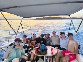 A group of friends enjoys a fun day on the water, capturing memories aboard a boat during sunset — perfect for fishing trips or summer outings.