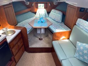 The cozy interior of a boat cabin featuring comfortable seating and a dining area, perfect for relaxing and enjoying meals while on the water.