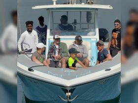 A cheerful group of friends and family enjoy a day on the water aboard a fishing boat, creating lasting memories together.