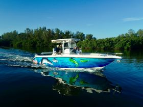 A vibrant boat cruises through calm waters, showcasing a lively group enjoying their time on the water — perfect for adventure seekers and fishing enthusiasts.