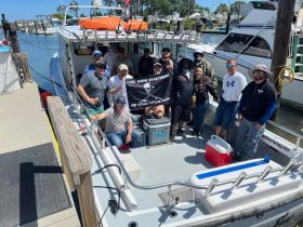 A lively group poses aboard a fishing charter boat, ready for an exciting day on the water — perfect for fishing adventures and group outings.