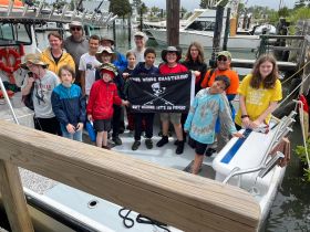 A lively group of kids and adults poses on a fishing charter, ready for an exciting day on the water. Perfect for family outings and fishing adventures.