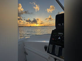 A stunning sunset view from the helm of a boat, showcasing the tranquil waters and a glimpse of the dashboard — perfect for evening cruises.