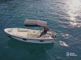 A person enjoys a sunny day aboard a speedboat, showcasing the thrill of boating on clear waters.