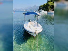 A picturesque view of a boat docked in clear waters, surrounded by scenic mountains and other vessels — perfect for exploring coastal destinations.