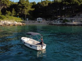 A small boat navigates the clear waters near a picturesque coastline, showcasing the beauty of a serene boating experience.