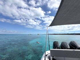 A swimmer enjoys the crystal-clear waters while a boat is anchored nearby, showcasing a perfect tropical getaway experience.