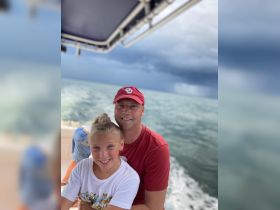 A joyful moment captured on a boat with a father and daughter enjoying their time on the water, showcasing the fun of family outings at sea.