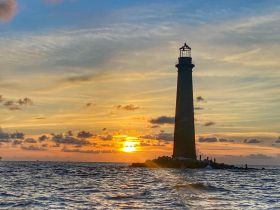 A stunning sunset view behind a lighthouse, casting a warm glow over the ocean — a picturesque moment perfect for capturing the beauty of coastal landscapes.