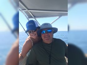 A cheerful couple enjoys their time on the boat, capturing a moment of joy on the water. Perfect for showcasing fun boating experiences.