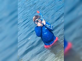 A child enjoys snorkeling in shallow waters, showcasing the fun and adventure of underwater exploration.