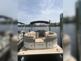 A well-maintained Bentley pontoon boat docked by the water, showcasing its spacious seating and inviting design, perfect for leisurely outings.
