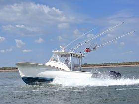 A sleek speedboat navigates through the water, showcasing its impressive design and fishing gear — perfect for adventurous outings on the water.