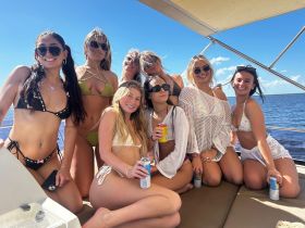 A lively group of friends enjoys a sunny day on the water, celebrating with drinks and laughter aboard a boat — perfect for summer parties and fun outings.