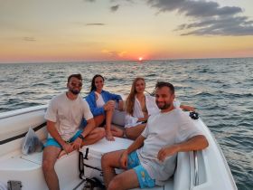 A group of friends enjoys a beautiful sunset on a boat, creating unforgettable memories on the water.