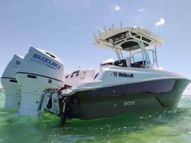 A sleek Welkcraft speedboat equipped with powerful Suzuki engines glides through clear waters, showcasing its modern design and performance capabilities.