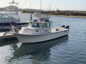 A fishing boat named 'KRAKEN' docked at the marina, showcasing its sturdy design and fishing gear, perfect for a day on the water.