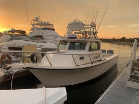 A beautiful shot of the 'KRAKEN' boat docked at sunset, showcasing its sleek design against a vibrant sky.