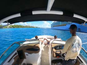A group enjoys a scenic boat ride with a cruise ship in the background, capturing the essence of relaxation and adventure on the water.