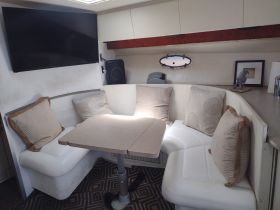 Cozy interior seating area of a boat featuring plush cushions and a dining table, perfect for relaxing and enjoying meals while on the water.