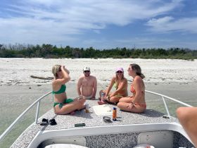 A lively group enjoys a sunny day on a boat, relaxing and having fun on the beach — the perfect setting for a summer getaway.