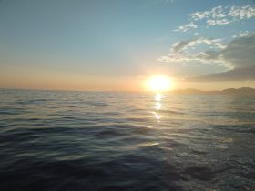 A serene sunset over calm ocean waters, creating a picturesque backdrop perfect for evening boat cruises.