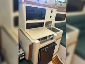 Interior view of a boat's kitchen area featuring a microwave, sink, and stove, showcasing the essential amenities for onboard cooking and dining.