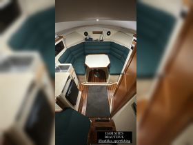 An inviting interior view of a boat's cabin featuring comfortable seating and a dining area, perfect for relaxing during your nautical adventures.