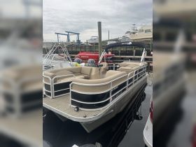 A sleek pontoon boat docked at the marina, showcasing its spacious seating and modern design — perfect for leisurely outings on the water.