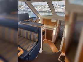 Interior view of a boat's cabin featuring comfortable seating and a well-equipped helm area, perfect for relaxing or navigating during a day on the water.
