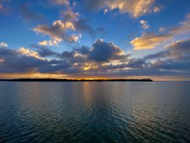 A stunning sunset over a tranquil waterway, with an island silhouette in the background — perfect for capturing the beauty of nature during a boating adventure.