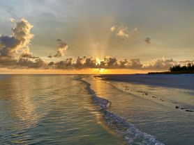 A breathtaking sunset casts golden rays over a tranquil beach, creating a serene coastal scene perfect for relaxation and reflection.