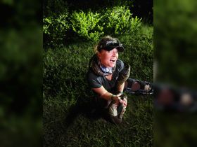 A woman interacts with a large snake in a nighttime setting, showcasing a thrilling human-animal encounter in the wild.