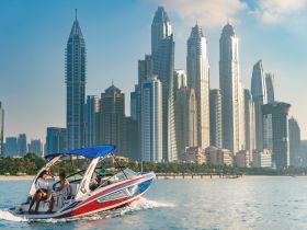 A stylish boat glides through the waters of Dubai, with skyscrapers in the backdrop, showcasing a perfect blend of urban luxury and water adventure.