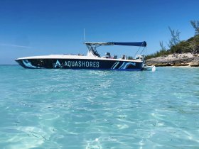 A sleek speedboat named AQUASHORES is docked in crystal-clear waters, showcasing the perfect setting for a day of adventure on the water.
