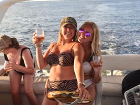 Two friends celebrate on a boat with cocktails, enjoying a fun day on the water — perfect for summer parties and gatherings.