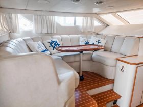 A cozy interior lounge area of a boat featuring comfortable seating and nautical-themed decor, perfect for relaxing during a day on the water.