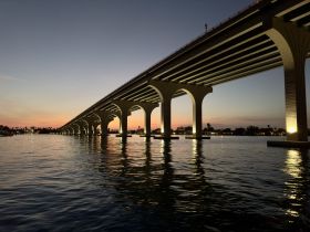 A scenic view of a bridge over water at sunset, capturing the tranquil ambiance of the evening.