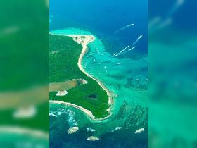 A stunning aerial view of a picturesque coastline with numerous boats dotting the turquoise waters, showcasing the beauty of island destinations perfect for boating adventures.