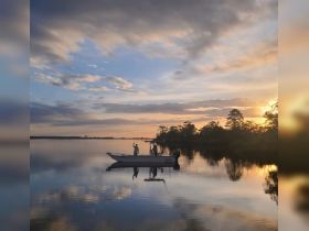 A serene sunset view with a fisherman waving from a boat, reflecting on calm waters — a perfect moment for fishing enthusiasts and nature lovers.