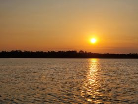 A serene sunset over calm waters, reflecting golden hues — a perfect backdrop for evening boat cruises.