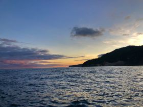 A serene sunset view over the water, showcasing the beautiful coastline and tranquil sea — perfect for peaceful evening cruises.