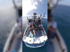 A lively group of friends enjoys cocktails aboard a fishing boat, celebrating their day on the water with smiles and good vibes.