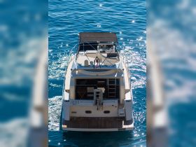A stunning aerial view of the yacht 'Leona' docked in sparkling blue waters, showcasing its elegant design and inviting outdoor space.