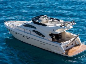 A stunning aerial view of a luxurious yacht cruising through clear blue waters, showcasing its elegant design and spacious deck.