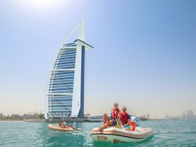 A couple enjoys a thrilling ride on a small boat near the iconic Burj Al Arab in Dubai, capturing the essence of adventure and stunning scenery in this vibrant city.