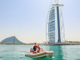 A couple enjoys a scenic ride on a small boat near the iconic Burj Al Arab in Dubai, showcasing the stunning architecture and vibrant waters.