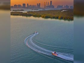 A stunning aerial view of two boats navigating through tranquil waters at sunset, with a vibrant city skyline in the background — perfect for showcasing boating adventures in urban settings.